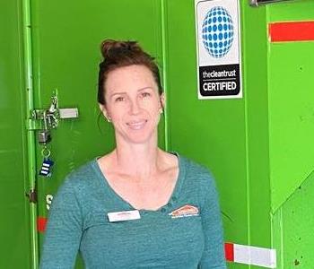 Female employee with red hair smiling in front of a green background